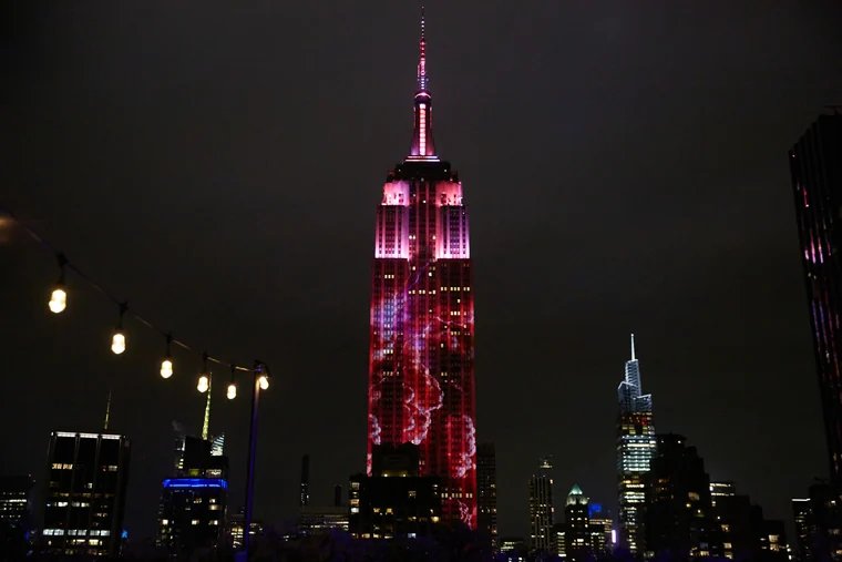 The Empire State Building lit in red at night above the New York skyline