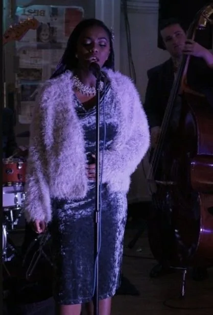 A singer in a fur jacket at a microphone, a double bass player behind her