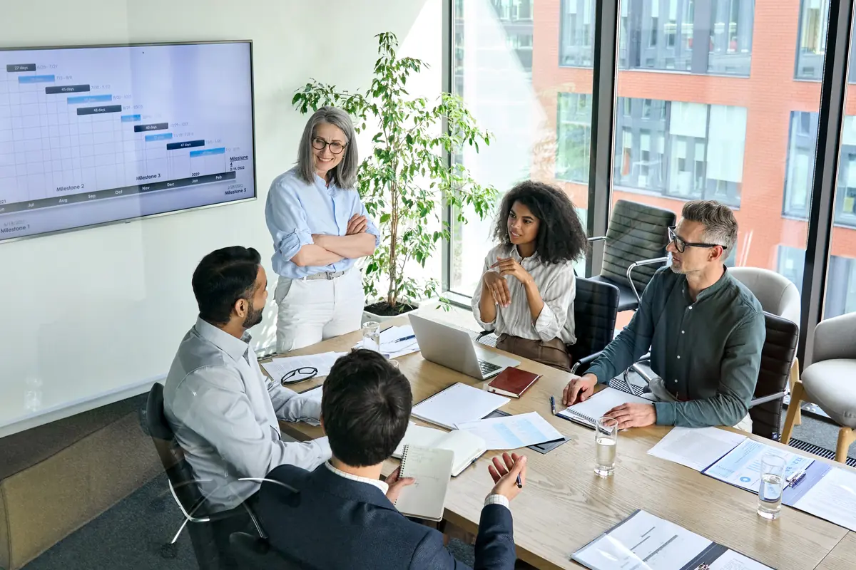 A boardroom meeting with a senior woman leading the discussion