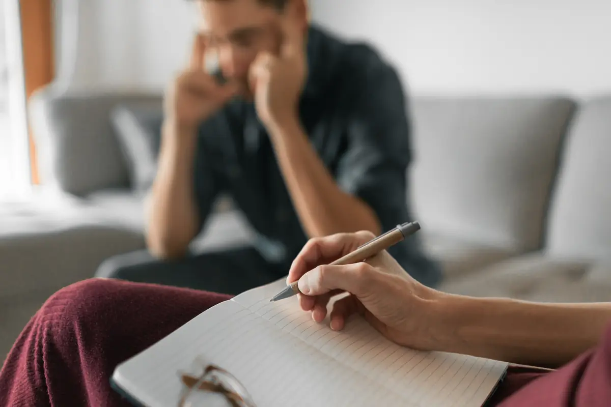 A coach taking notes while a man describes a difficult situation