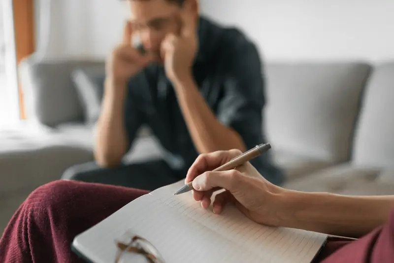 A coach taking notes while a man describes a difficult situation