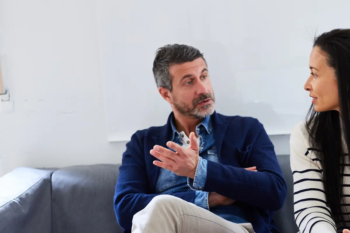 A man talking with a colleague on a sofa