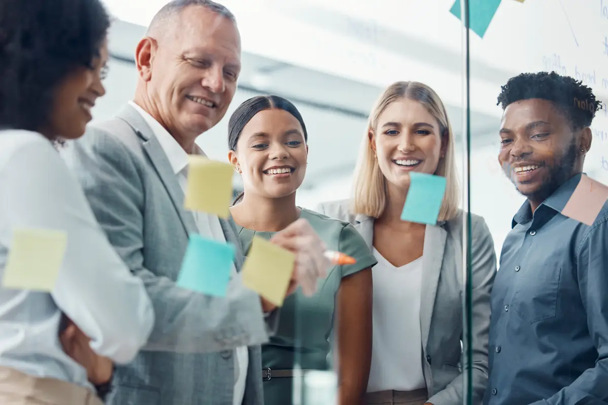 A diverse team brainstorming with sticky notes on a glass wall