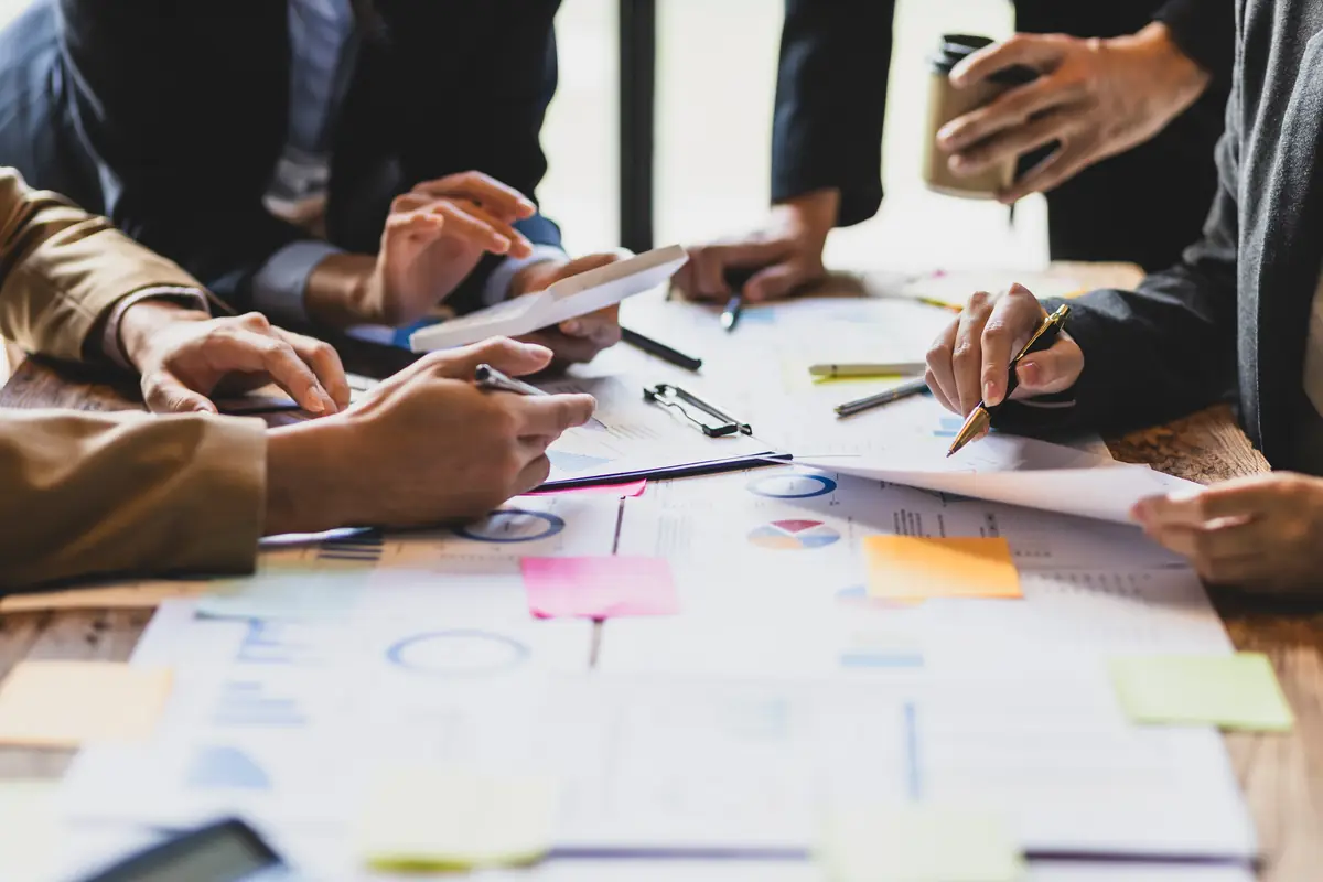 Hands working over papers and sticky notes at a planning session