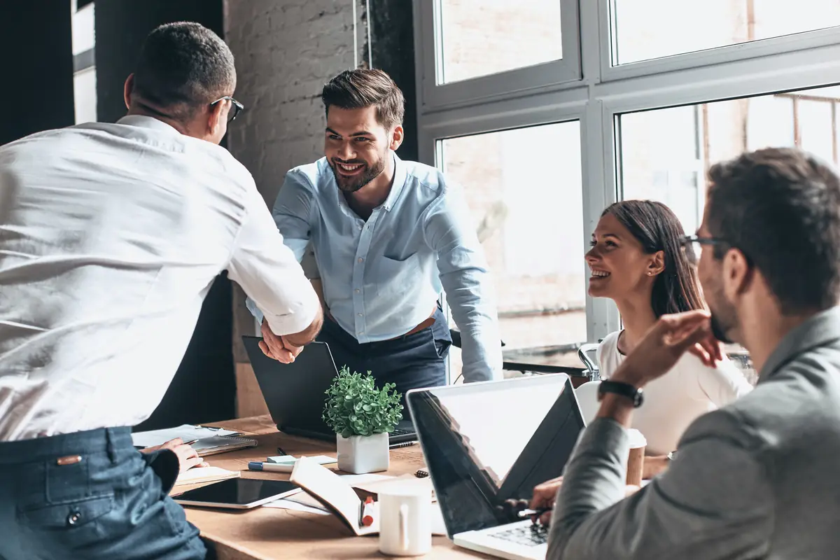 Colleagues shaking hands across a meeting table