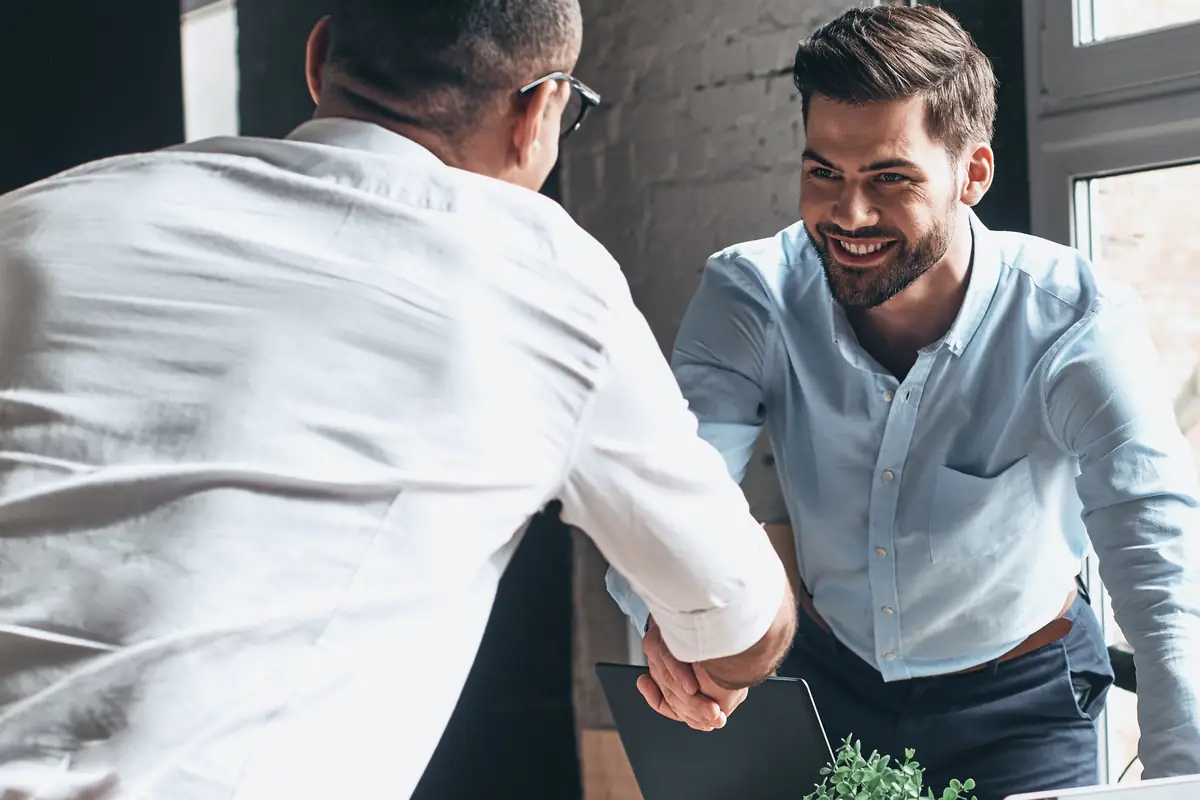 Two colleagues shaking hands across a table