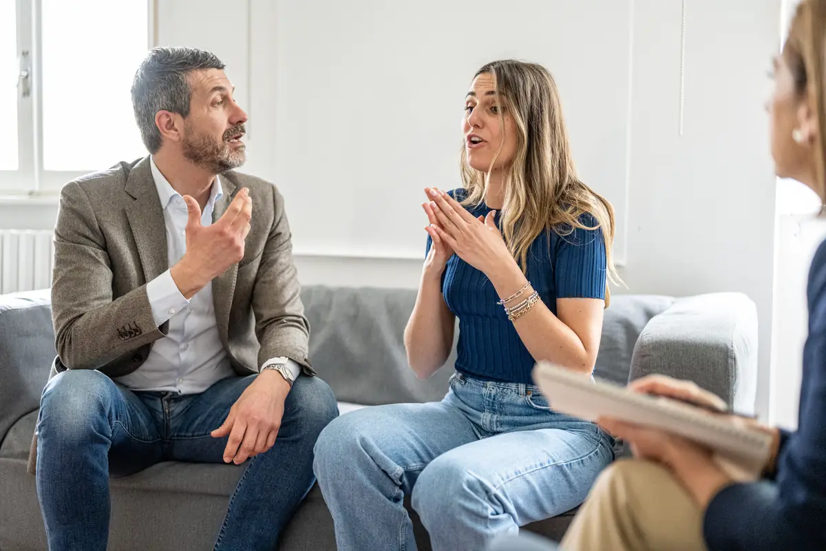 Two people in a heated discussion, with a facilitator taking notes