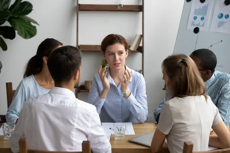A woman making a point in a team meeting while colleagues listen