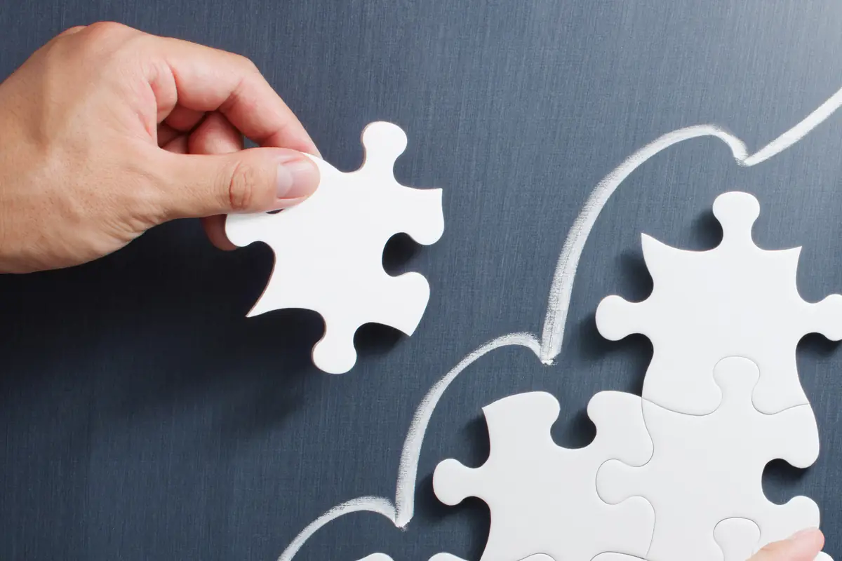 Hands placing a puzzle piece on a chalkboard