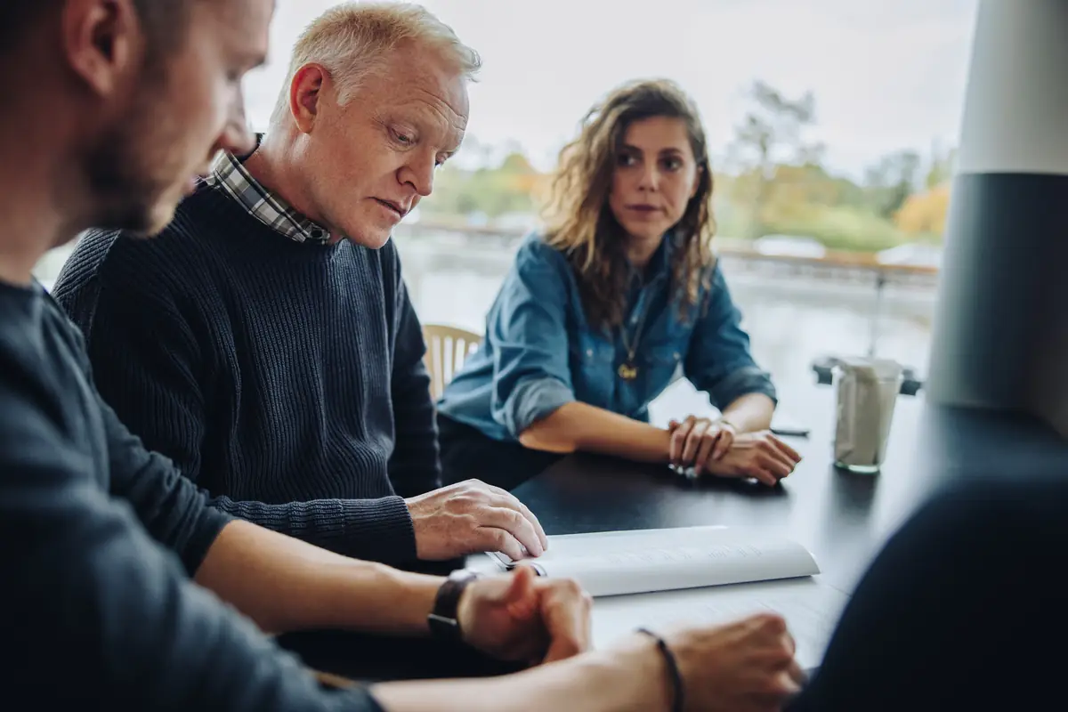 Three colleagues in a serious conversation at a table
