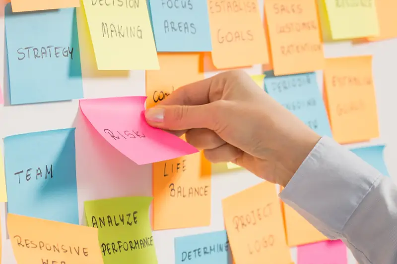 A hand placing a sticky note on a crowded board