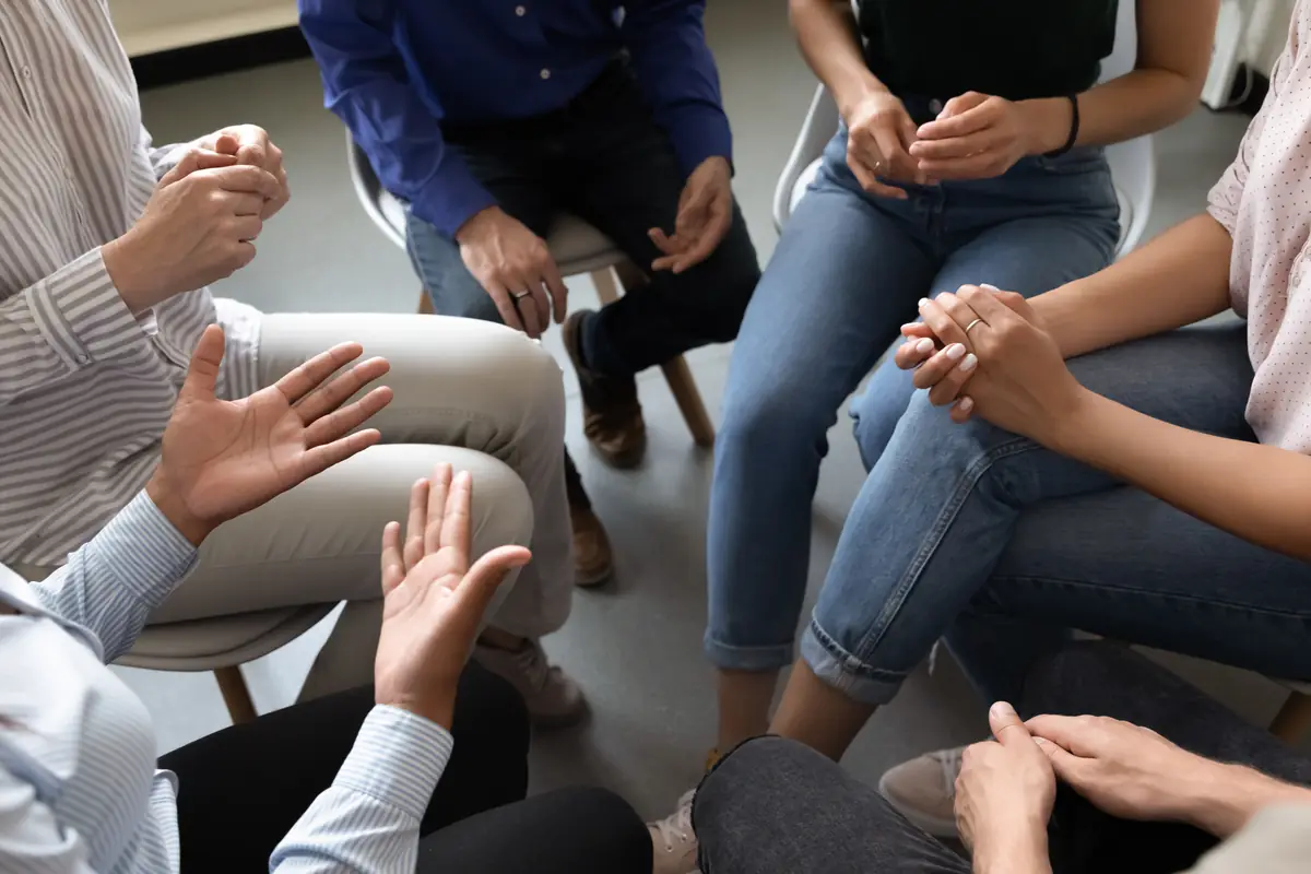 A support group in a circle, hands in view as people talk