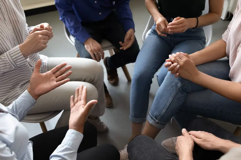 A support group in a circle, hands in view as people talk