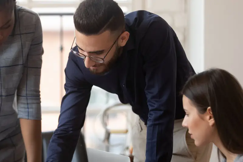 A colleague leaning over the table to explain a plan