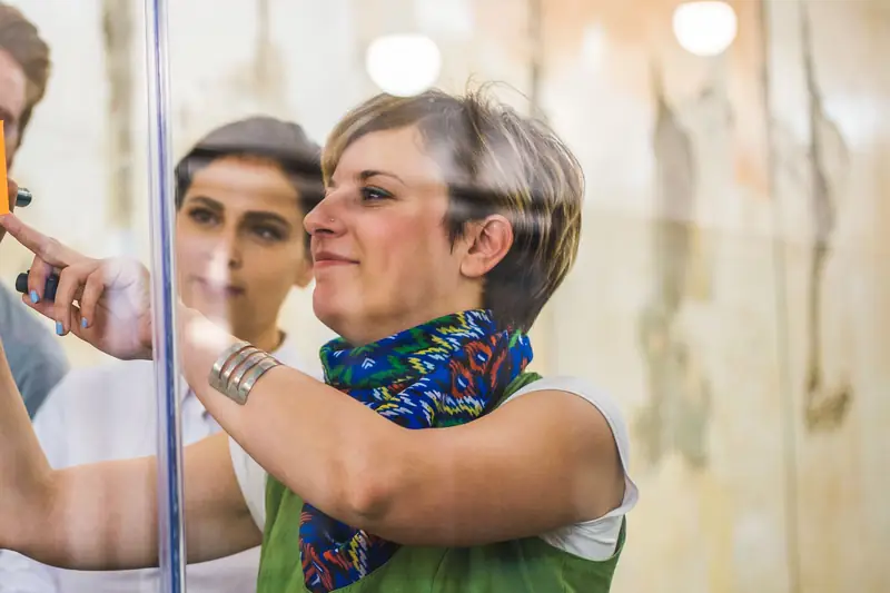A colleague adding a sticky note to a glass wall
