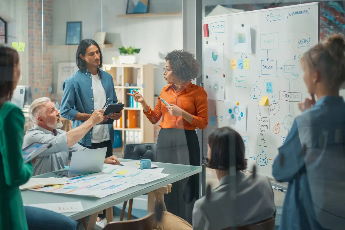A facilitator at a whiteboard running a team workshop